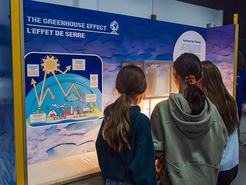 trois jeunes filles découvrent l'effet de serre grâce à une exposition interactive