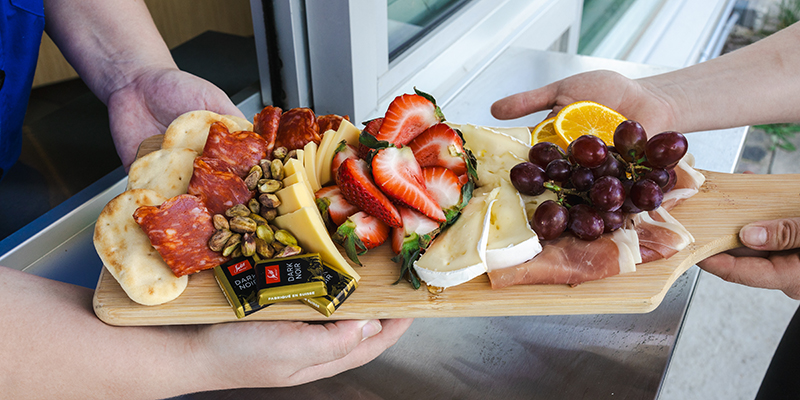 deux mains tenant un plateau de charcuterie
