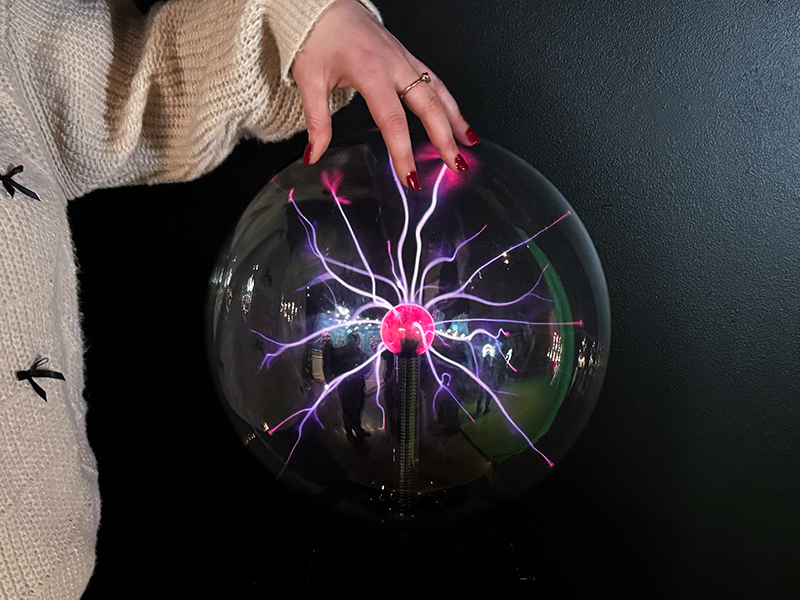 female hand touching an active van de graaff generator