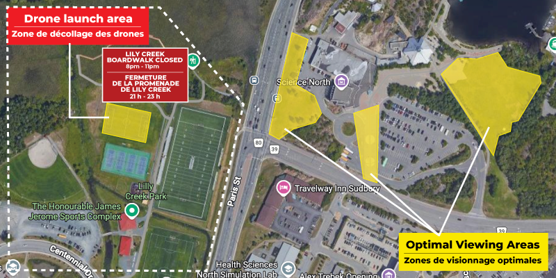 Aerial map of the Science North area showing marked Canada Day drone show zones. Yellow shapes highlight optimal viewing locations, while a red box labels the drone launch area. Roads, parking lots, buildings, and Lily Creek Park are visible, with notes indicating closures of the Lily Creek boardwalk during the event.