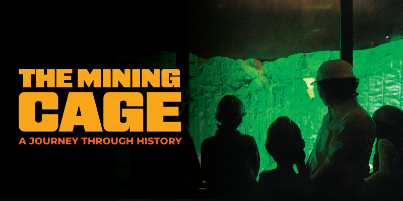 Promotional graphic with bold orange text reading “The Mining Cage: A Journey Through History” beside silhouetted visitors wearing helmets, standing in a dim space with a glowing green rock wall display.